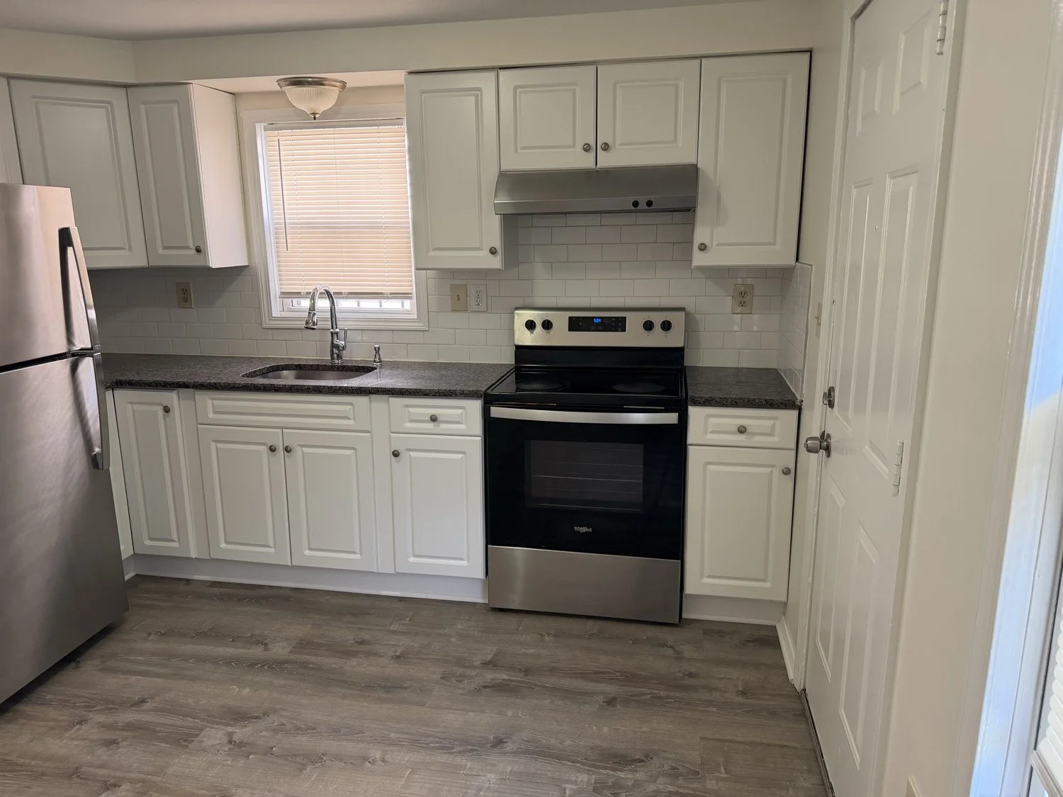Medina kitchen project with white cabinetry, subway tile backsplash, stainless steel appliances and wood-look flooring