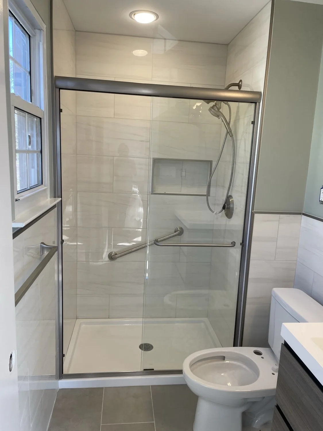 A tiled shower with glass doors and a recessed shower niche.